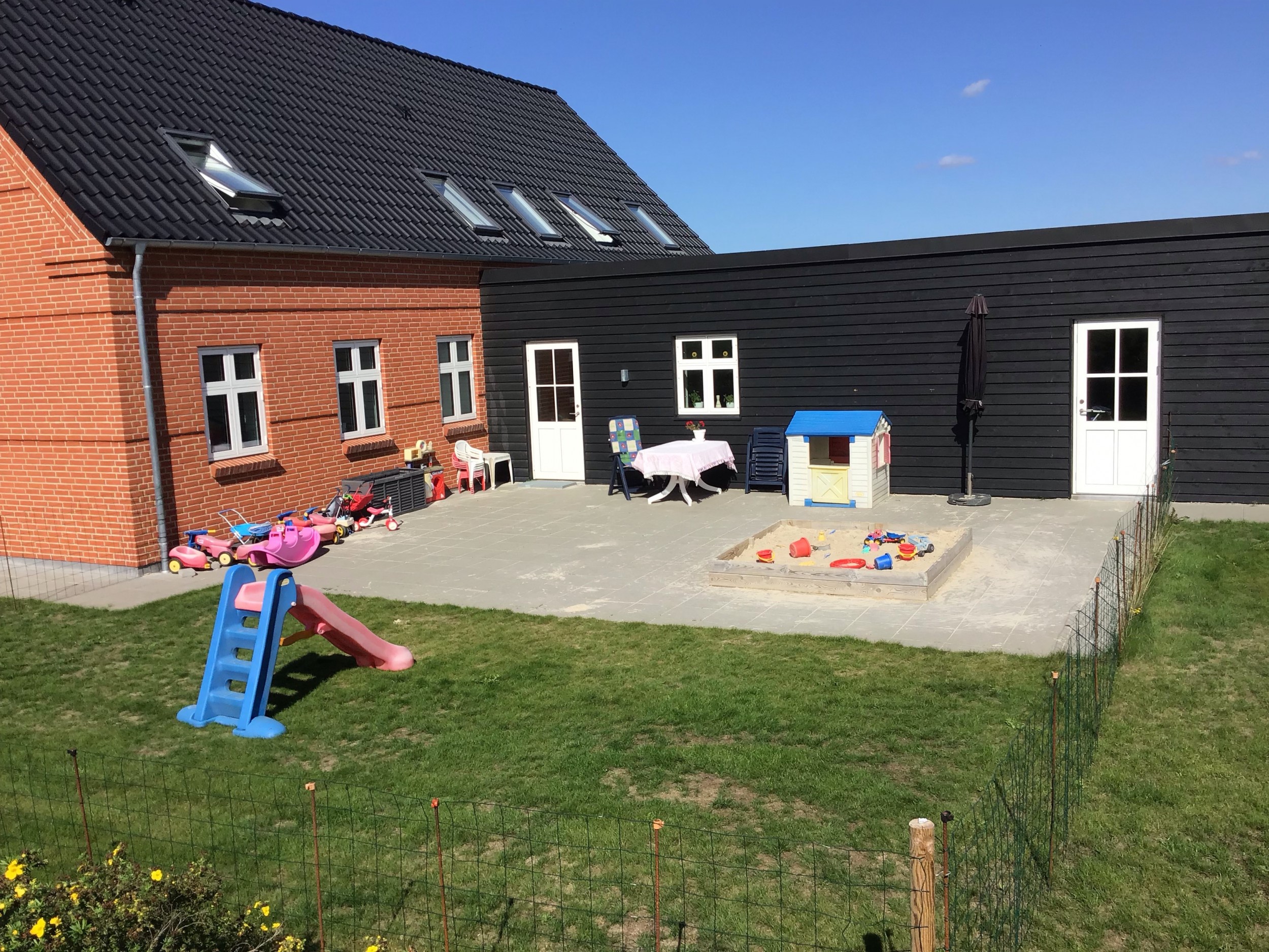 Sanne har en have med et stort legeområde med sandkasse, legehus og rutsjebane